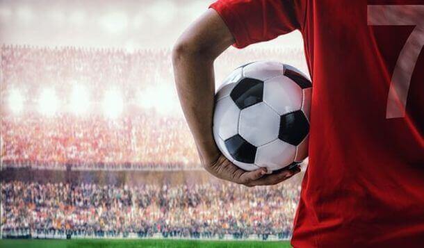 Football player holding the ball on the side of the pitch