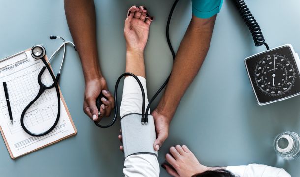 Healthcare data analytics help predict the number of patients to improve staffing. This image shows an available medical professional measuring patients' blood pressure. 